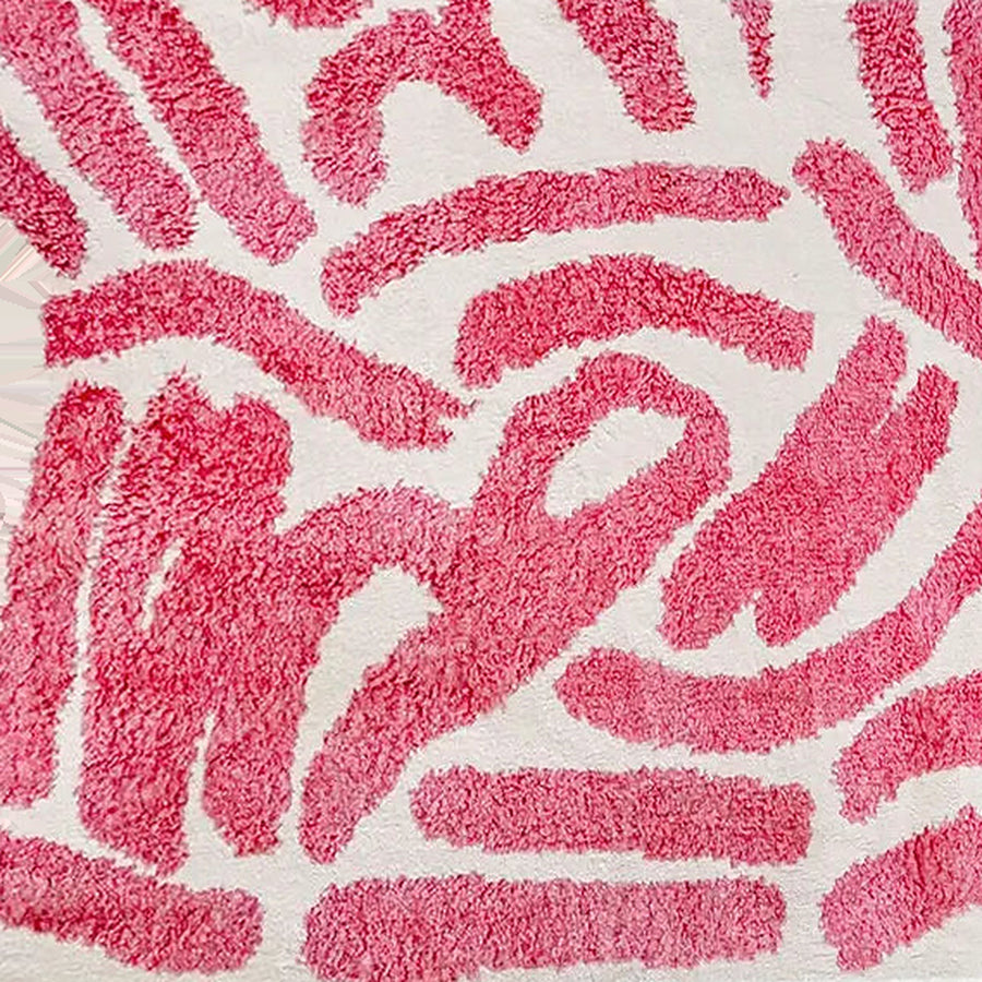Gros plan sur le velours du tapis berbère coloré tafukt, écru à traits framboise