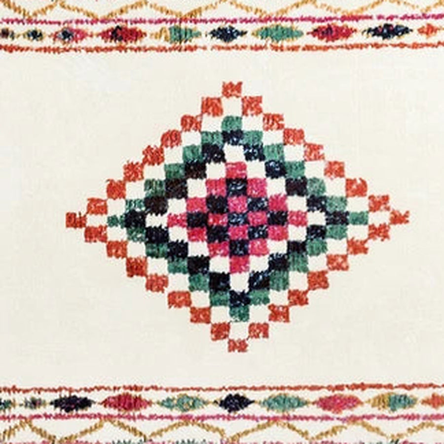 Gros plan sur le velours du tapis berbère coloré taziri, médaillon rose et vert
