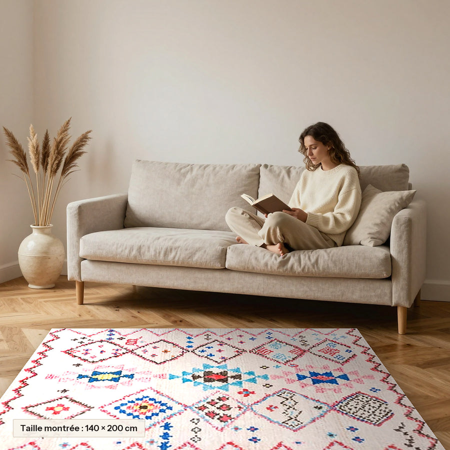 Tapis berbère coloré Tamassant, losanges rose et turquoise posé devant un canapé, taille 140 × 200 cm