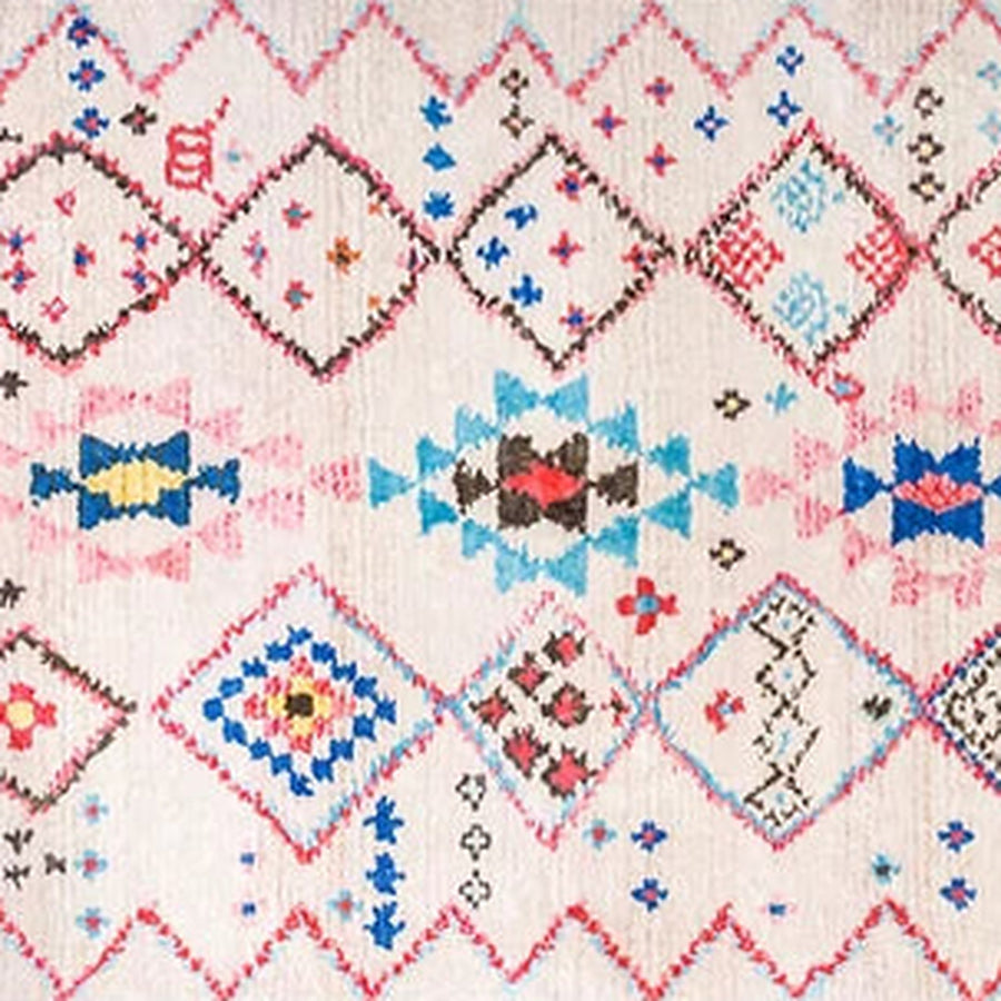Gros plan sur le velours du tapis berbère coloré tamassant, losanges rose et turquoise