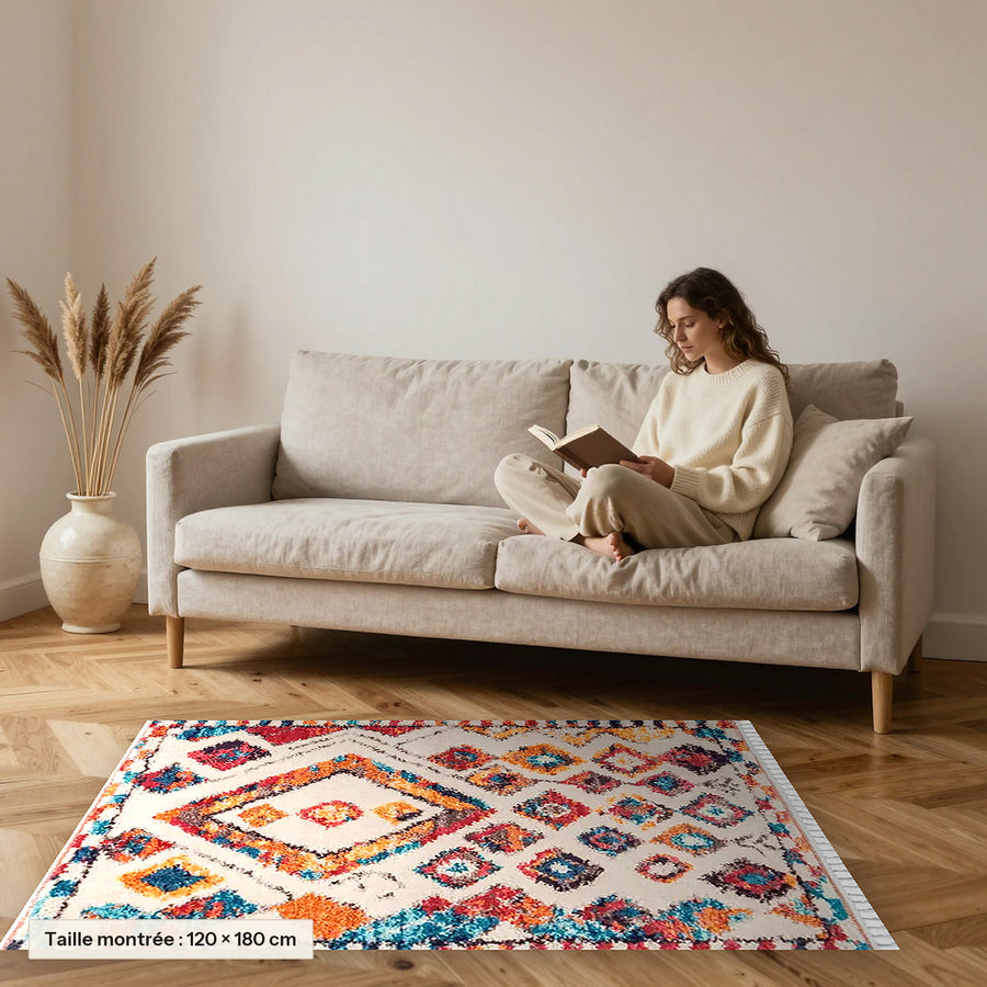 Tapis berbère coloré Tinhinan, écru à losanges vifs posé devant un canapé, taille 120 × 180 cm