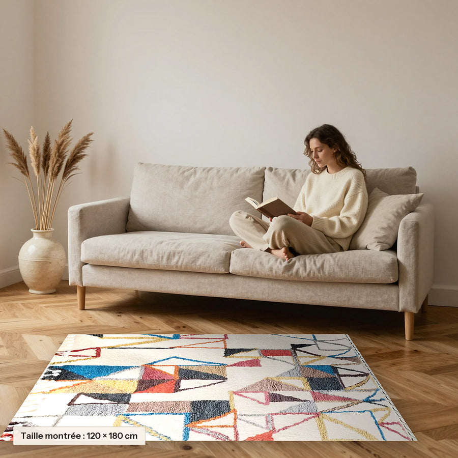 Tapis berbère coloré Maya, écru et triangles colorés posé devant un canapé, taille 120 × 180 cm