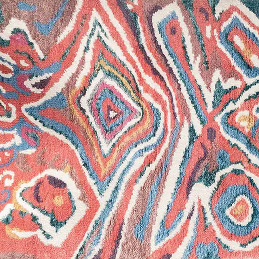 Gros plan sur le velours du tapis berbère coloré idir, bleu et corail