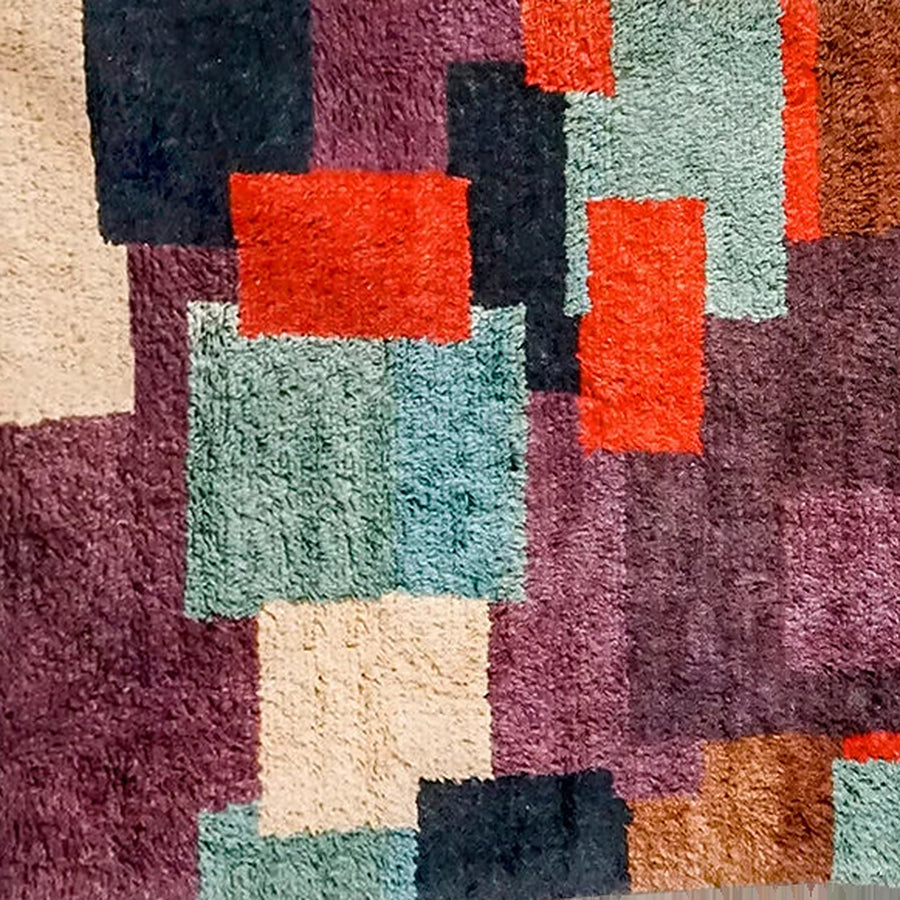 Gros plan sur le velours du tapis berbère coloré tafsut, patchwork prune et orange
