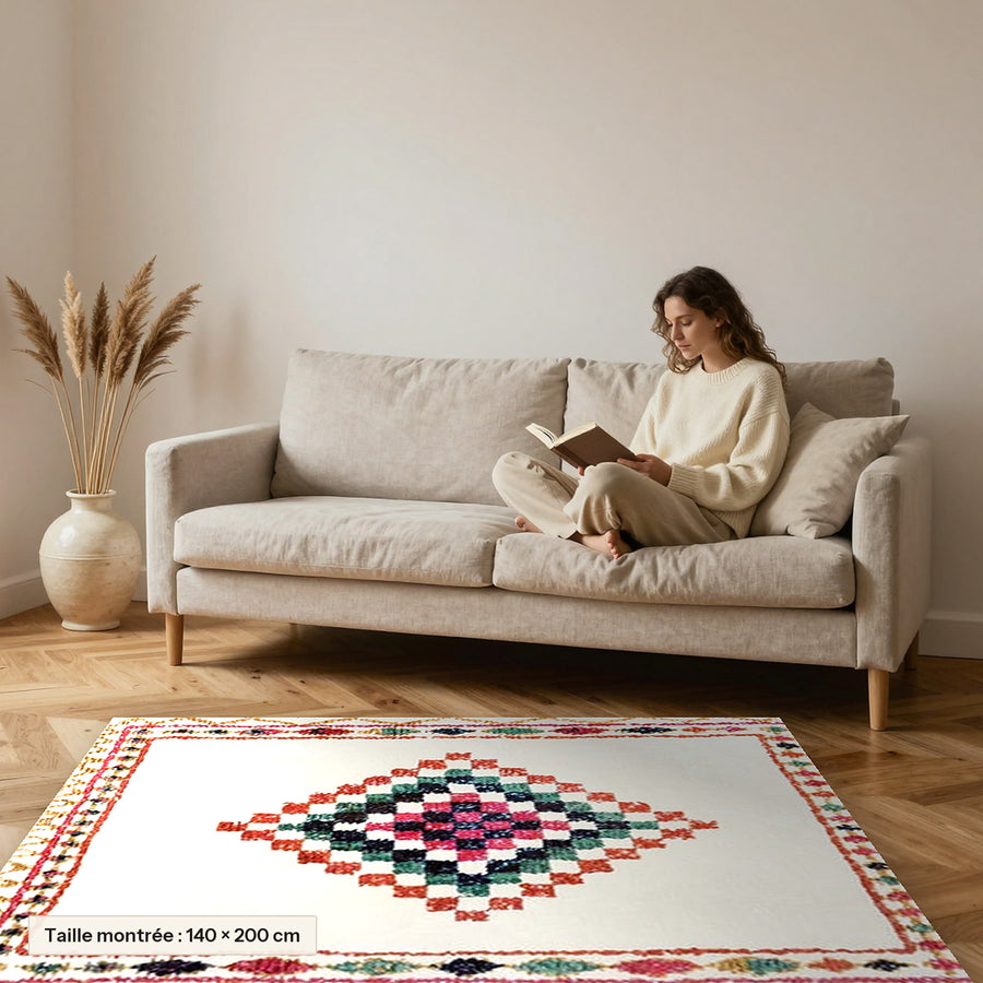 Tapis berbère coloré Taziri, médaillon rose et vert posé devant un canapé, taille 140 × 200 cm
