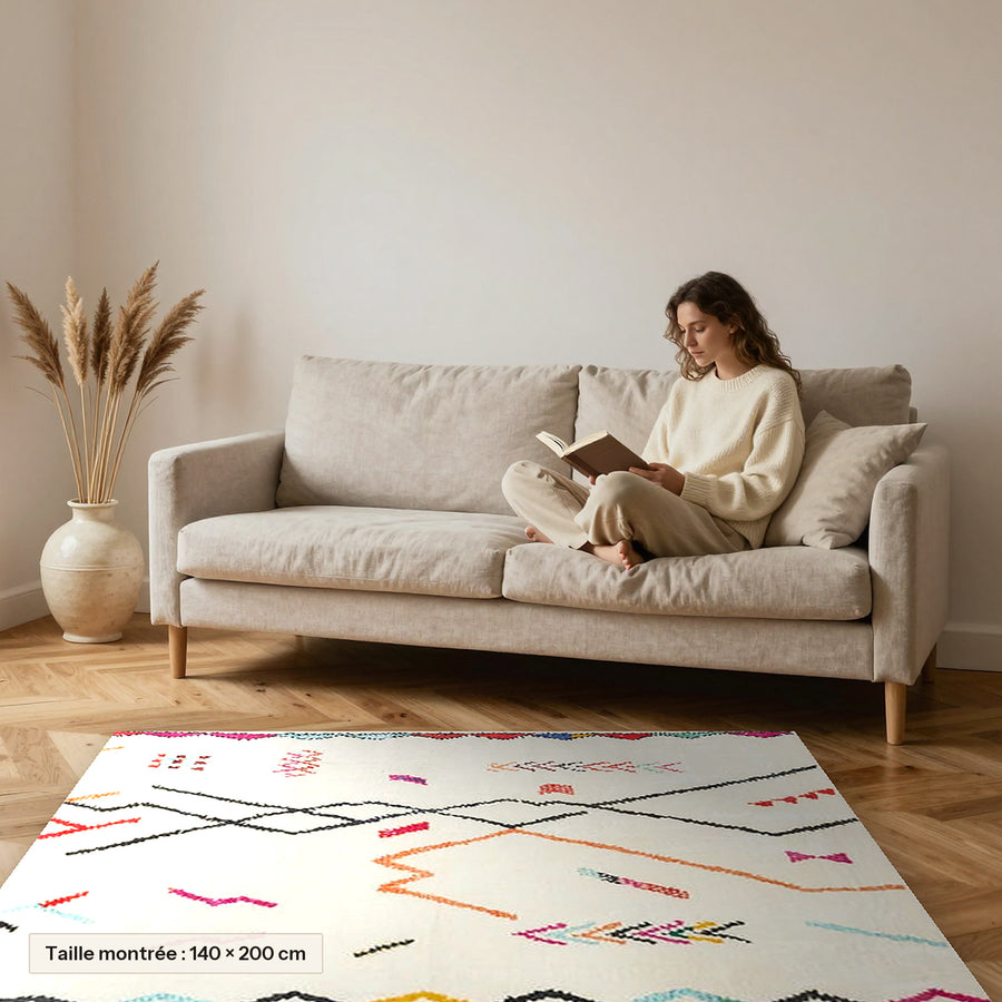 Tapis berbère coloré Tifa, traits libres colorés posé devant un canapé, taille 140 × 200 cm