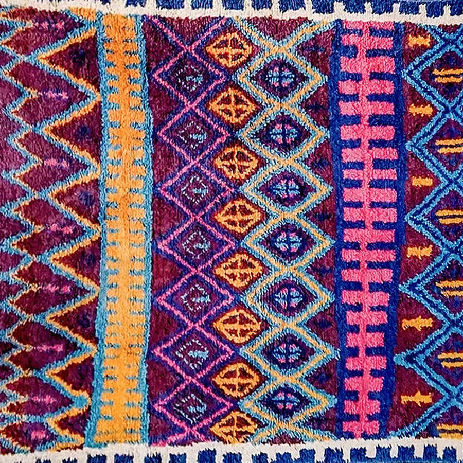 Gros plan sur le velours du tapis berbère coloré thiyya, violet et rose