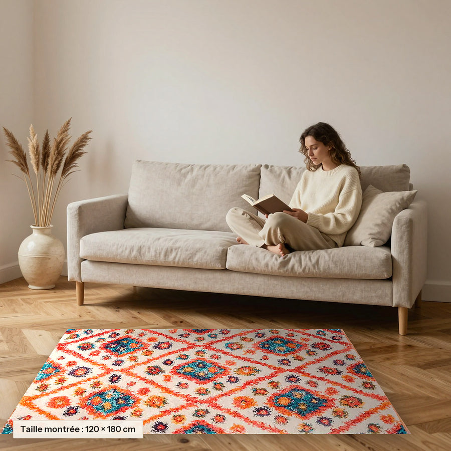 Tapis berbère coloré Anya, orange et turquoise posé devant un canapé, taille 120 × 180 cm