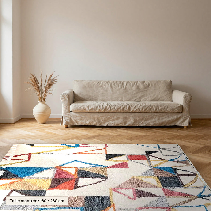 Tapis berbère coloré Maya, écru et triangles colorés posé dans un salon, taille 160 × 230 cm