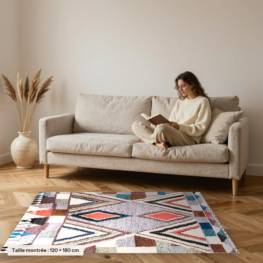 Tapis berbère coloré Numinsa, écru et chevrons colorés posé devant un canapé, taille 120 × 180 cm