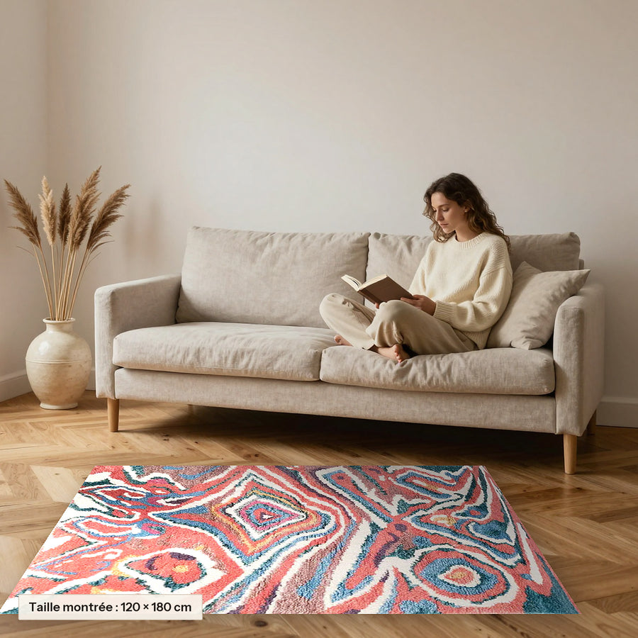 Tapis berbère coloré Idir, bleu et corail posé devant un canapé, taille 120 × 180 cm