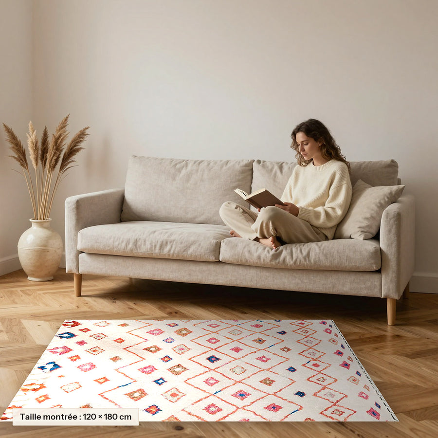 Tapis berbère coloré Amnir, écru et petits losanges posé devant un canapé, taille 120 × 180 cm