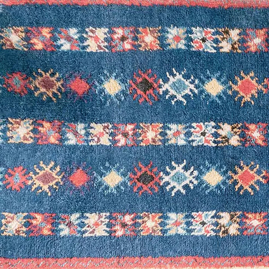 Gros plan sur le velours du tapis berbère coloré ayyur, bleu rayé