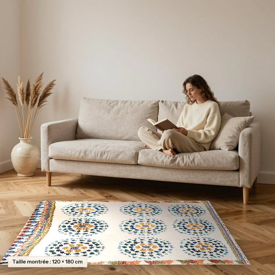 Tapis berbère coloré Ziri, écru et rosaces ocre posé devant un canapé, taille 120 × 180 cm