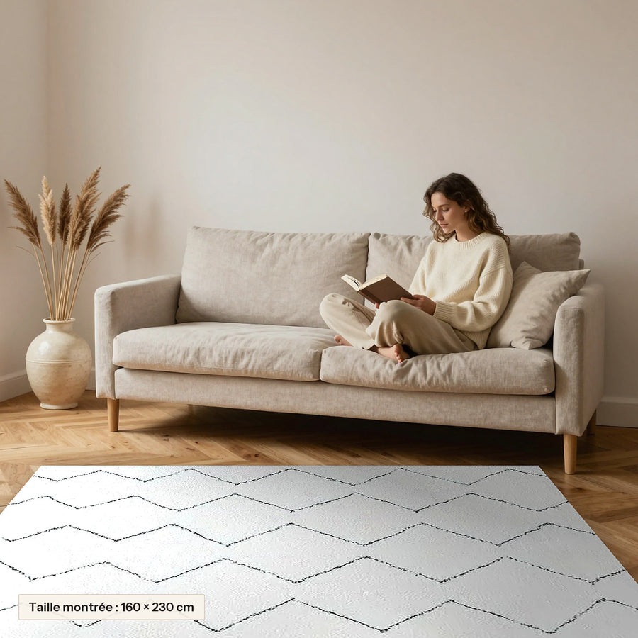 Tapis Beni Ouarain Titrit, écru, grands losanges posé devant un canapé, taille 160 × 230 cm