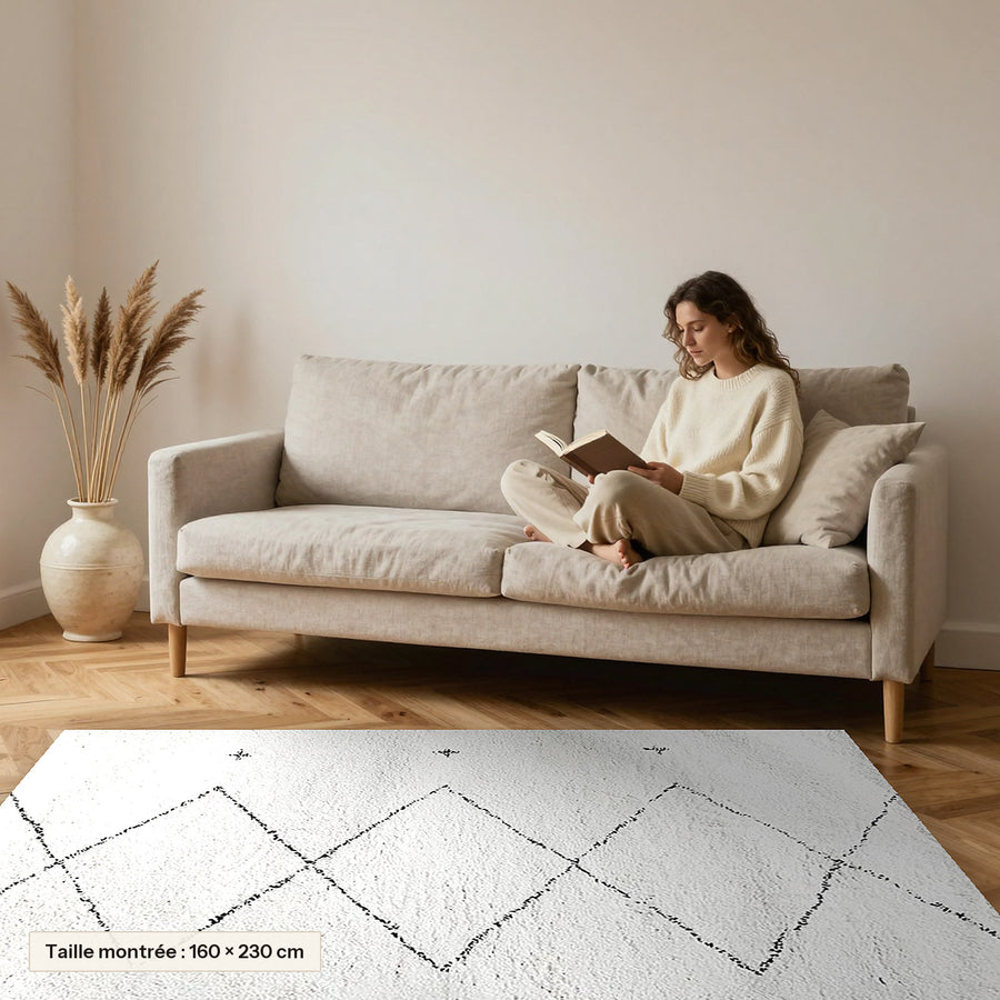 Tapis Beni Ouarain Tifawt, blanc, losanges et croix posé devant un canapé, taille 160 × 230 cm