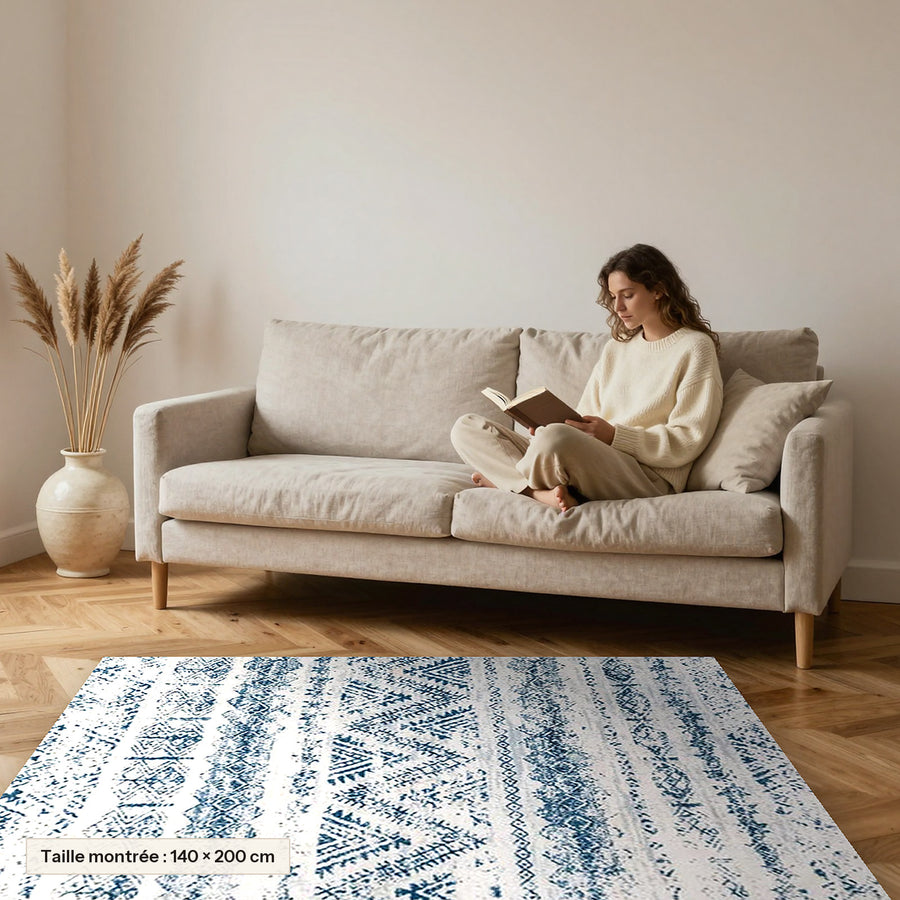 Tapis Beni Ouarain Taskurt, bandes bleu délavé posé devant un canapé, taille 140 × 200 cm